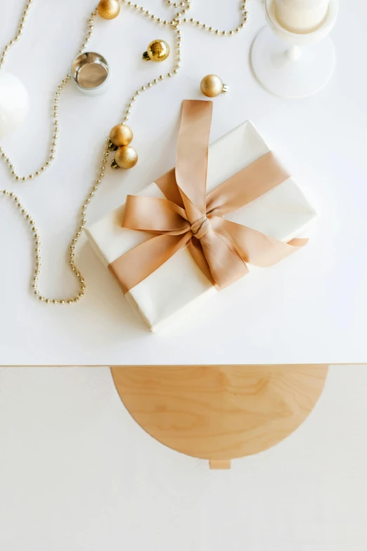 a gift sitting on top of a white table, by Eden Box, minimalism, emitting light ornaments, light tan, brightly-lit, ilustration