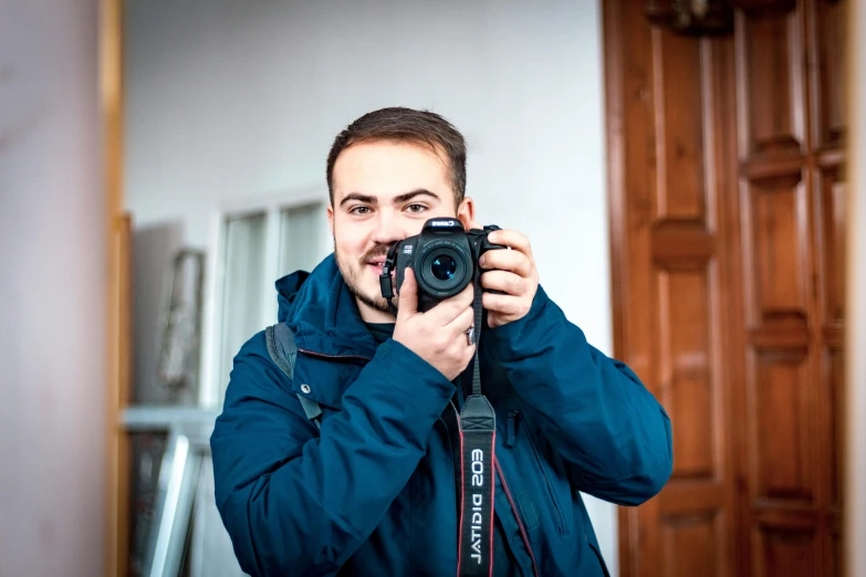 a man taking a picture of himself in a mirror, a picture, by Julia Pishtar, pexels contest winner, holding a dslr camera, ukraine. professional photo, smiling at camera, home photography portrait