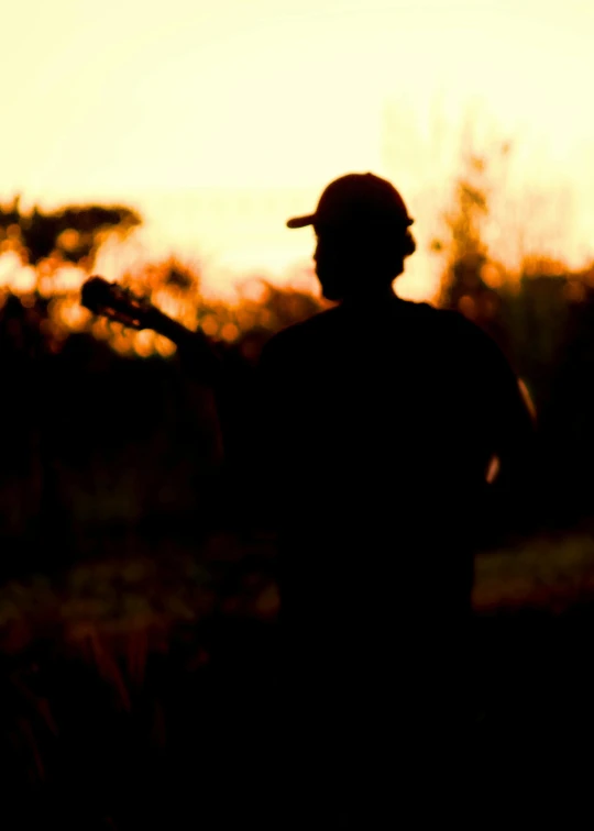 a silhouette of a man playing a guitar, standing in the savannah, profile image, large)}], profile pic