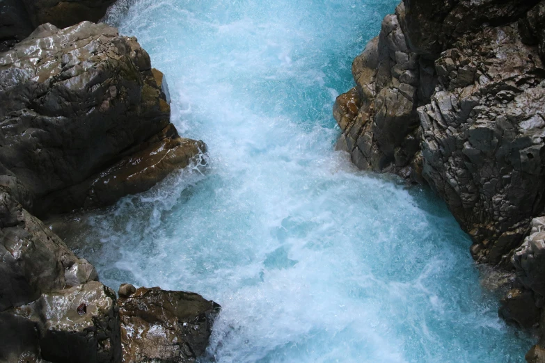 a man standing on top of a rock next to a river, pexels contest winner, hurufiyya, azure waves of water, whirlpool, thumbnail, brown and cyan color scheme