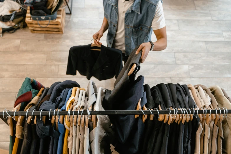a man standing in front of a rack of clothes, trending on pexels, happening, wearing a dark shirt and jeans, at checkout, federation clothing, thumbnail
