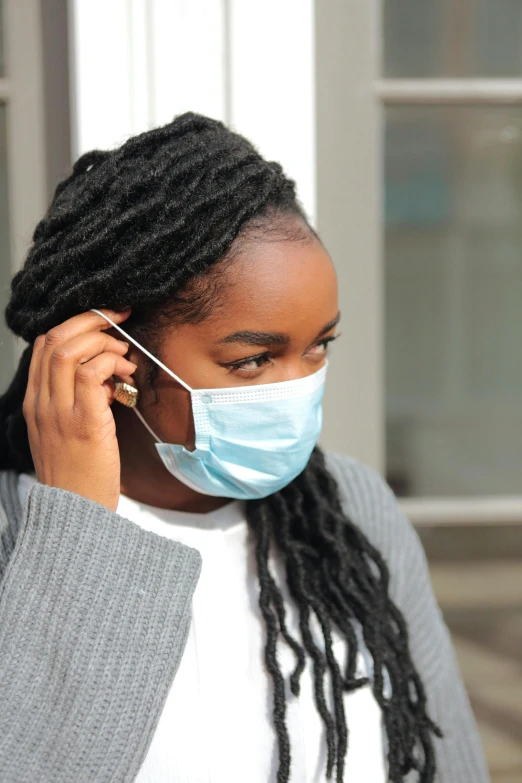 a woman wearing a face mask while talking on a cell phone, photo of a black woman, surgical supplies, sharp focus »