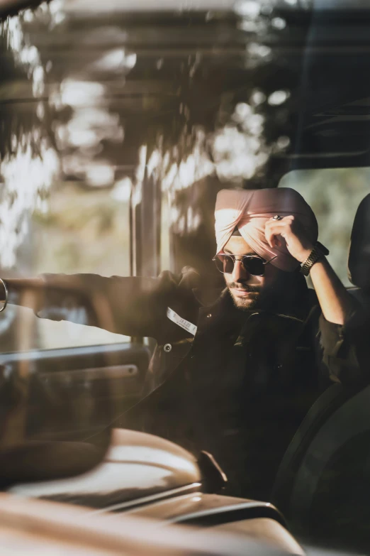 a man sitting in the passenger seat of a car, inspired by Manjit Bawa, trending on pexels, beret and sunglasses, sunfaded, australian, black car