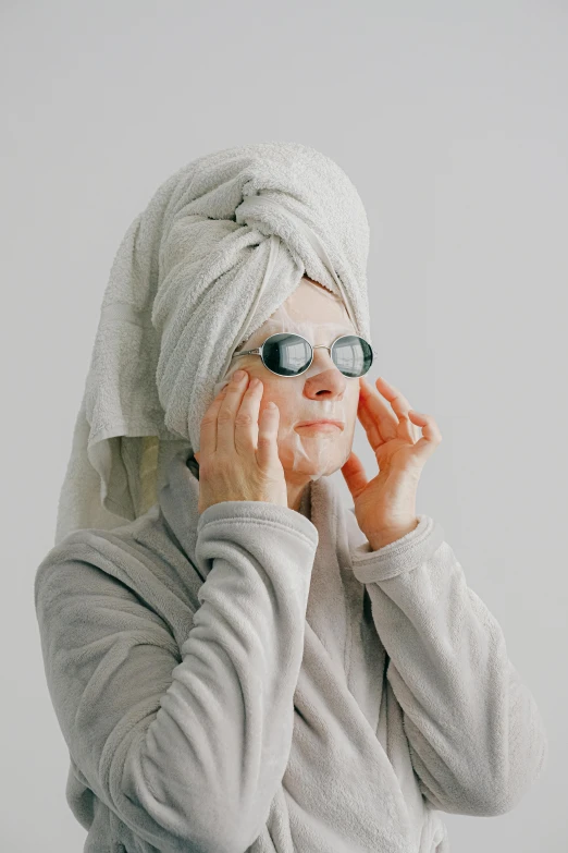 a woman with a towel wrapped around her head, trending on pexels, photorealism, wearing glack glasses, 5 5 yo, silicone skin, pale grey skin