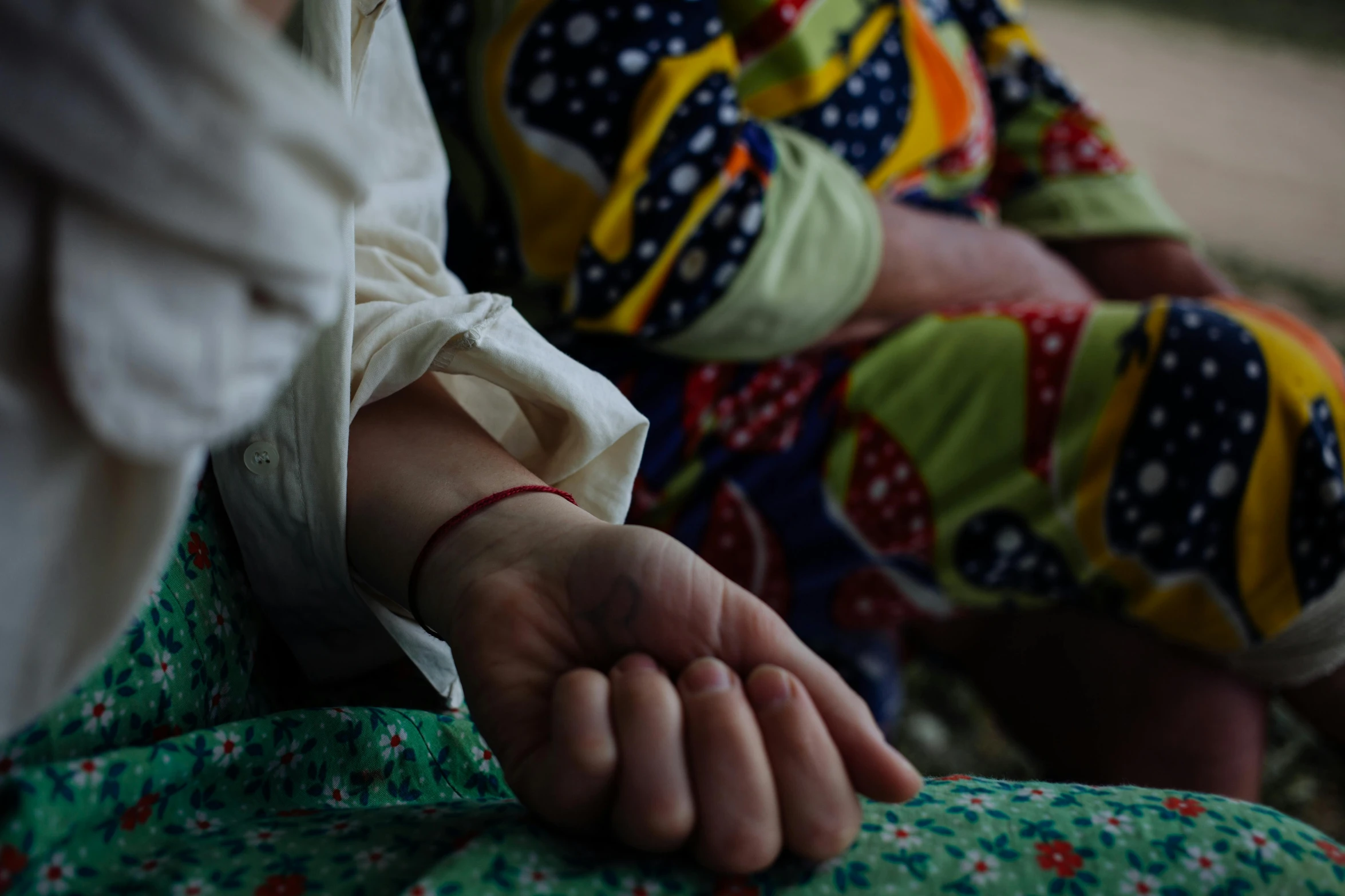 a close up of a person holding a persons hand, by Nathalie Rattner, hurufiyya, colourful clothing, 15081959 21121991 01012000 4k, documentary photo, sitting down