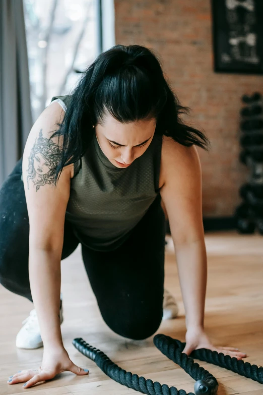 a woman doing a jump rope exercise in a gym, a tattoo, pexels contest winner, renaissance, crawling on the ground, gif, concerned, color photo