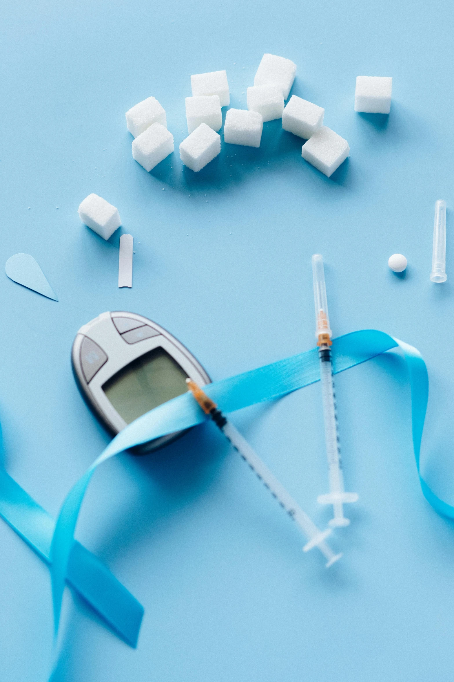 an electronic device sitting on top of a blue table, holding a syringe, sugar, white ribbon, iconic design