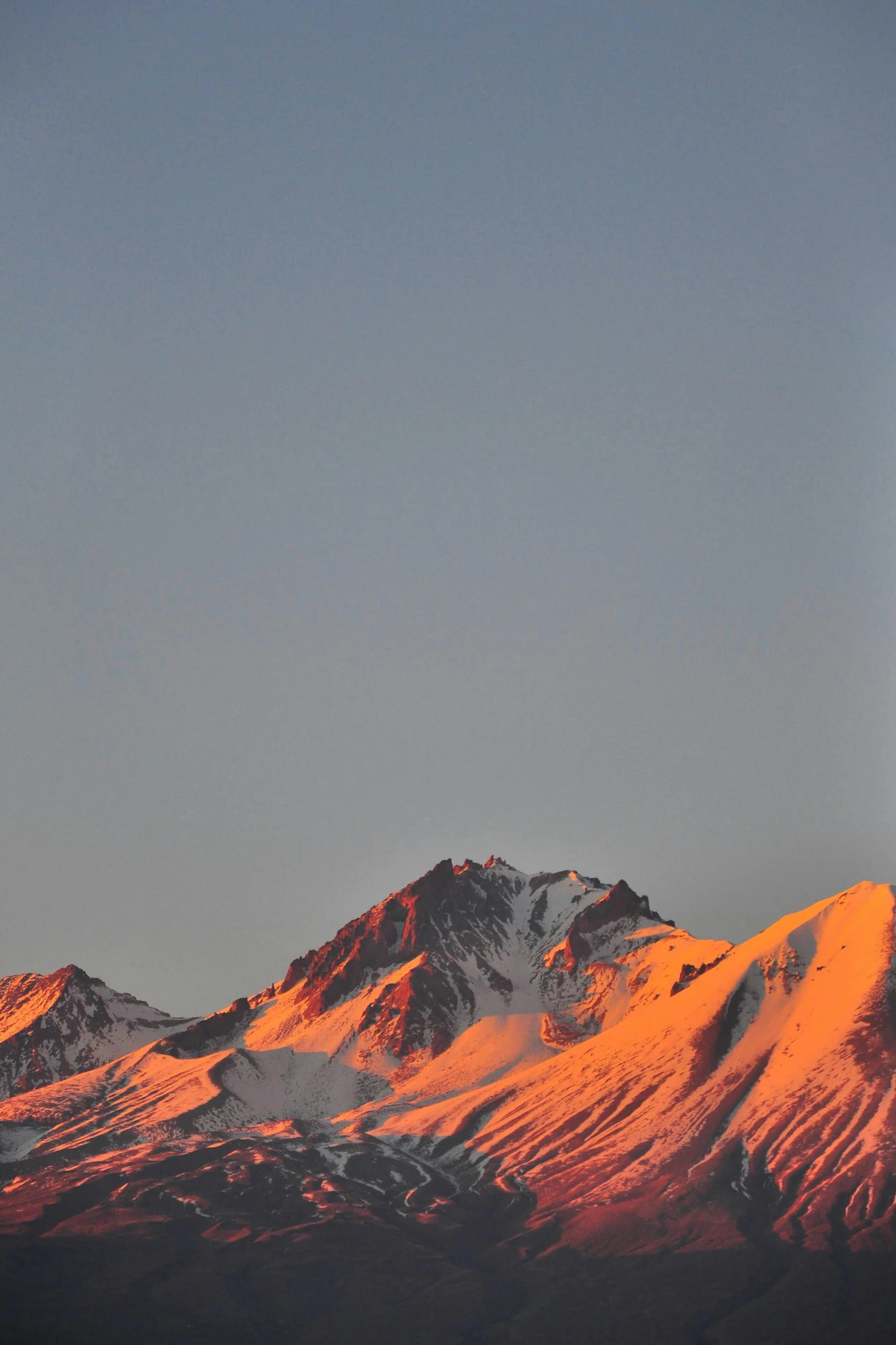 the sun is setting on the snow covered mountains, by Peter Churcher, minimalism, lava in the background, clear skies, light show, late summer evening