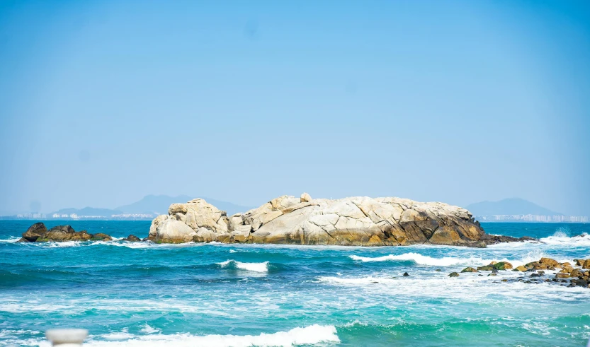 a man riding a surfboard on top of a wave covered beach, unsplash, rock formations, clear blue sky, peruvian looking, the city of santa barbara