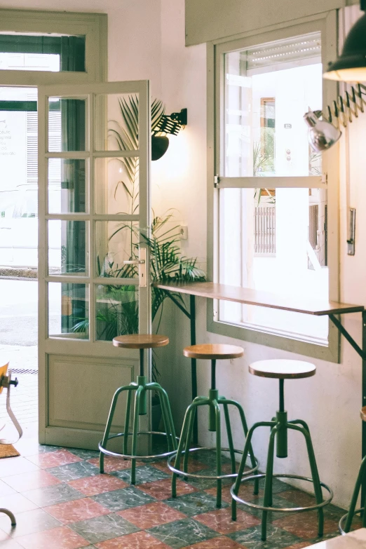 a living room filled with furniture and lots of windows, inspired by Barthélemy Menn, trending on unsplash, in a bright cafe, stools, in barcelona, greens)