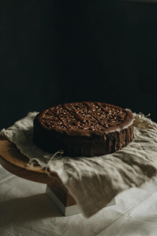 a chocolate cake sitting on top of a wooden plate, by Daniel Seghers, pexels contest winner, renaissance, back facing, silk, greek, made of glazed