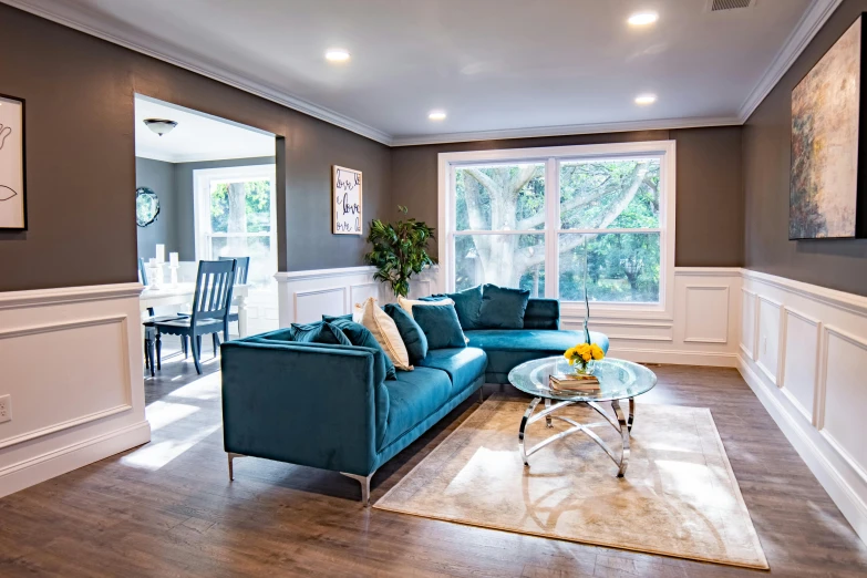 a living room filled with furniture and a large window, featured on instagram, dark teal couch, pristine clean design, high details photo, youtube thumbnail