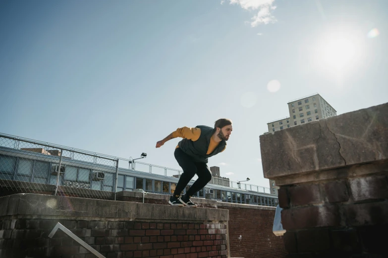 a man riding a skateboard down the side of a brick wall, by Lee Gatch, pexels contest winner, happening, parkour, sunny day time, on rooftop, worksafe. cinematic