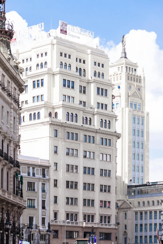 a group of people walking down a street next to tall buildings, inspired by Tomàs Barceló, neoclassicism, freddy mamani silvestre facade, neoclassical tower with dome, exterior view, zoomed out view