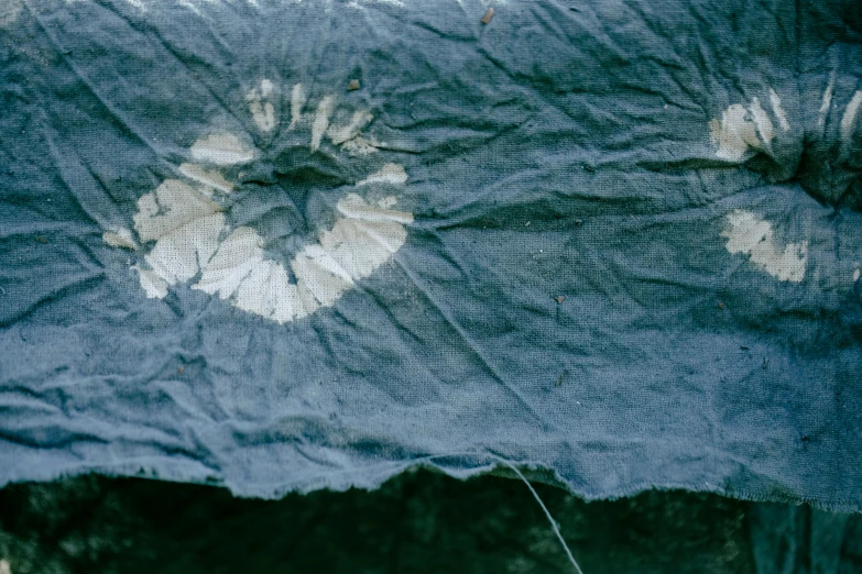 a piece of blue fabric with white flowers on it, a silk screen, unsplash, land art, damaged clothes, slate, datura, tie-dye