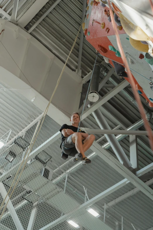 a woman climbing up the side of a climbing wall, by Juriaen van Streeck, happening, complex ceiling, sitting in a crane, looking towards camera, 1km tall