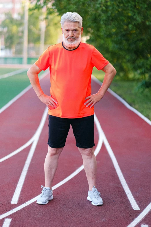 a man standing on a running track with his hands on his hips, a portrait, shutterstock, bushy white beard, wearing an orange t shirt, knees weak, an elderly