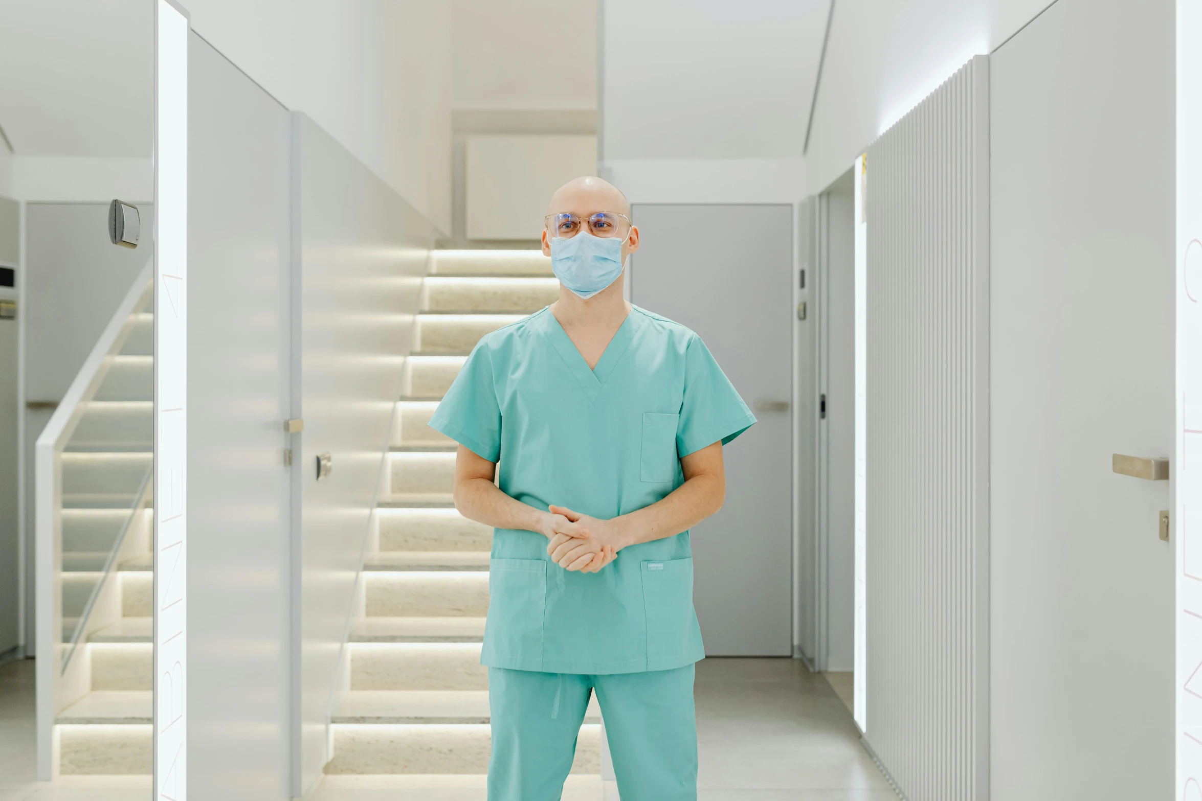 a man in scrubs standing in a hallway, by Évariste Vital Luminais, pexels contest winner, rem koolhaas, masked doctors, frank quitely, portrait photo