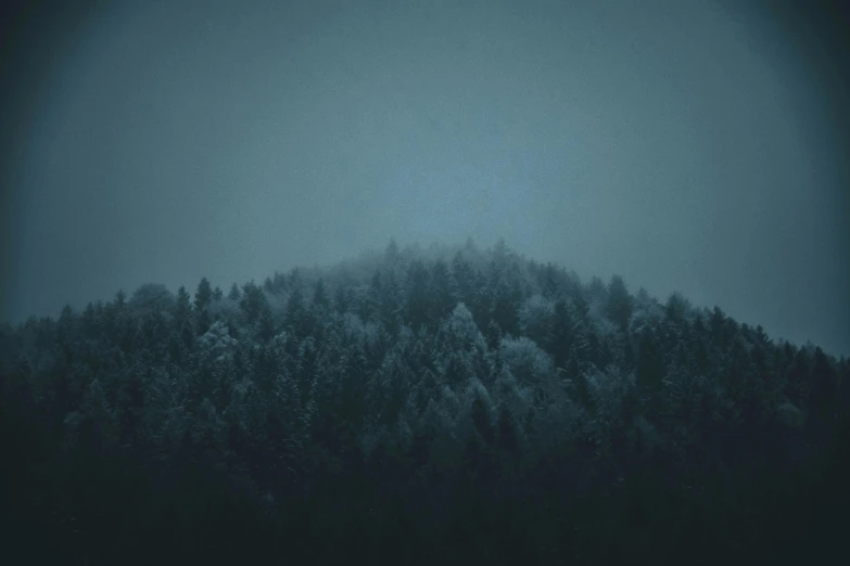 a mountain covered in snow next to a forest, inspired by Elsa Bleda, unsplash contest winner, tonalism, desaturated blue, mysterious - eerie - ominous, photography of todd hido, teal aesthetic