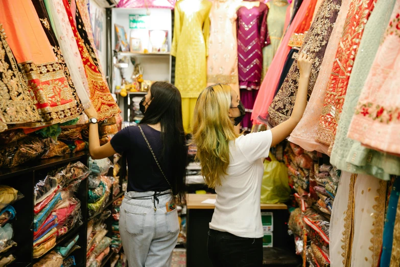 a couple of women standing next to each other in a store, trending on unsplash, hurufiyya, streets of mumbai, in chippendale sydney, middle eastern style vendors, inspect in inventory image