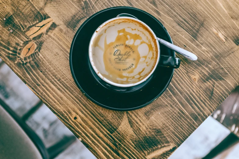 a cup of coffee sitting on top of a wooden table, by Daniel Gelon, pexels contest winner, fan favorite, aussie baristas, soup, finely painted