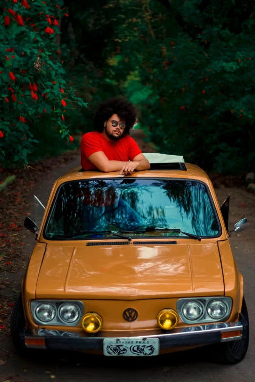 a man sitting on top of a car with a surfboard on top of it, an album cover, by Ras Akyem, pexels contest winner, renaissance, in front of a forest background, red car, garden road, with afro