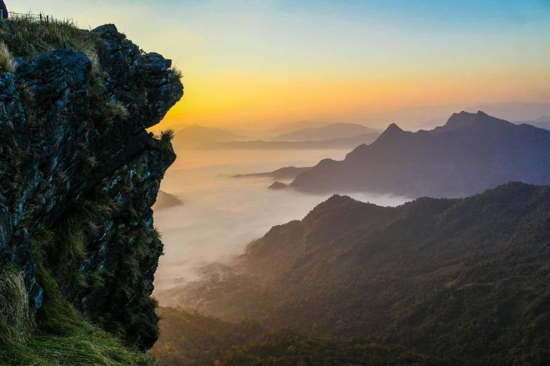 a person standing on top of a cliff, by Peter Churcher, pexels contest winner, romanticism, sri lankan landscape, mountain sunrise, panorama view, gentle mists