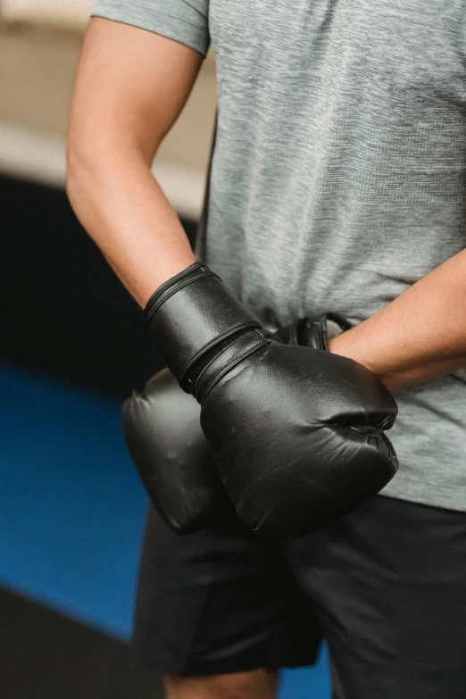 a man holding a pair of boxing gloves, unsplash, wrapped in black, no - text no - logo, thumbnail, teenage boy