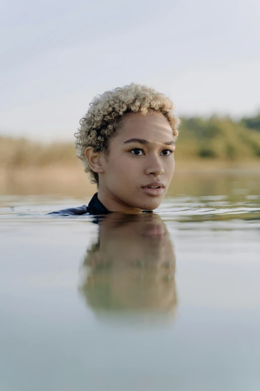 a woman swimming in a body of water, short blonde afro, looking off into the distance, nonbinary model, 2019 trending photo