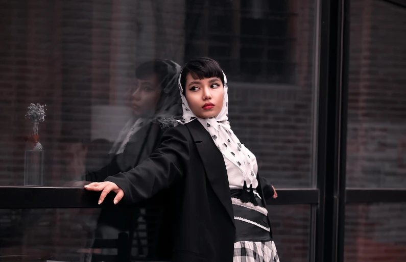 a woman standing in front of a window, an album cover, inspired by Modest Urgell, pexels contest winner, realism, wearing a black jacket, beautiful iranian woman, young asian woman, attractive androgynous humanoid