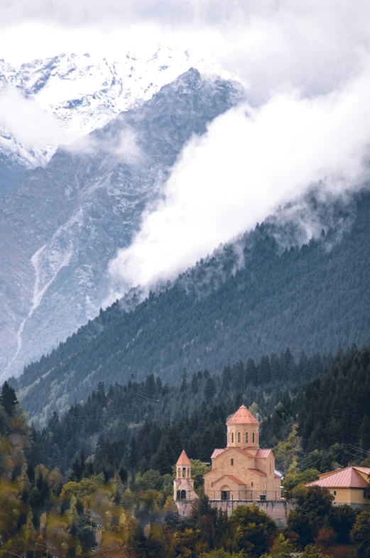 a church sitting on top of a lush green hillside, inspired by Istvan Banyai, trending on unsplash, romanesque, snowy peaks, autum, kurdistan, castle made of clouds
