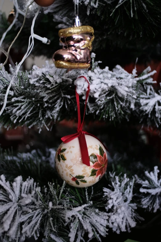 a close up of a christmas ornament on a tree, cream, ceramic, floral, cosy