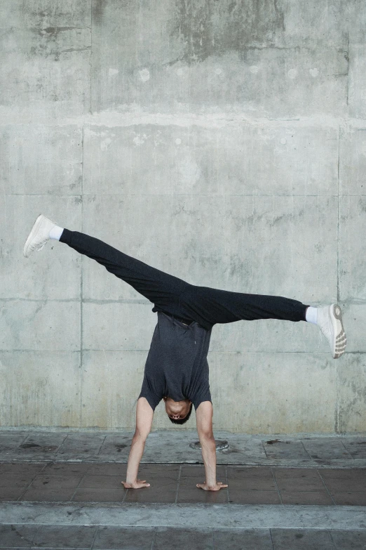 a man doing a handstand in front of a wall, unsplash, arabesque, plain background, scientific photo, teenage boy, headshot