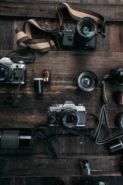 a group of cameras sitting on top of a wooden table, a picture, by Adam Marczyński, flatlay, adventure, indoor shot, medium format