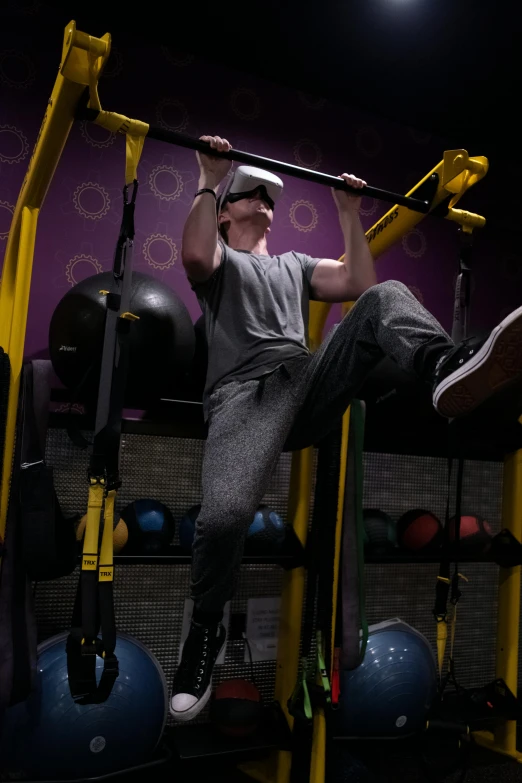 a man sitting on a pull up bar in a gym, by John Luke, happening, in a planet fitness, virtual reality, yellow and charcoal, gorecore