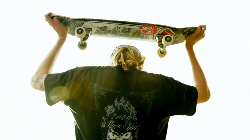 a man holding a skateboard over his head, by Winona Nelson, bottom shot, profile image