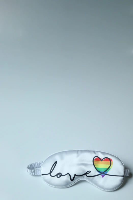 a white eye mask with a rainbow heart on it, inspired by Karl Völker, unsplash, signatures, soccer players timo werner, photographed for reuters, german