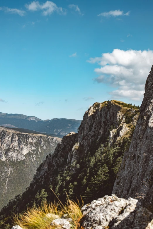 a man standing on top of a mountain next to a cliff, by Niko Henrichon, pexels contest winner, les nabis, 4 k cinematic panoramic view, southern european scenery, today\'s featured photograph 4k, panorama