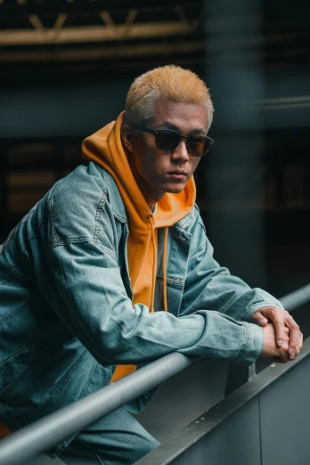 a man in a jacket and sunglasses leaning on a railing, inspired by Gang Hui-an, trending on unsplash, yellow hair, asian male, denim, gray and orange colours