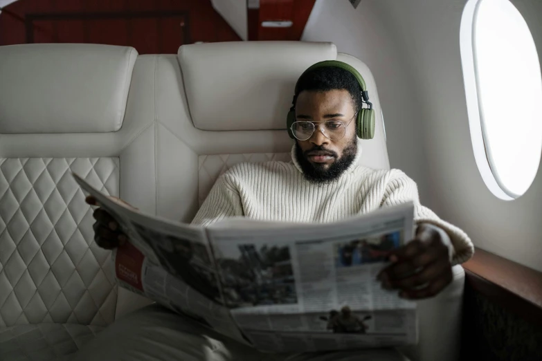 a man sitting in an airplane reading a newspaper, an album cover, pexels contest winner, afrofuturism, jaylen brown, wearing gaming headset, overcast, luxury and elite