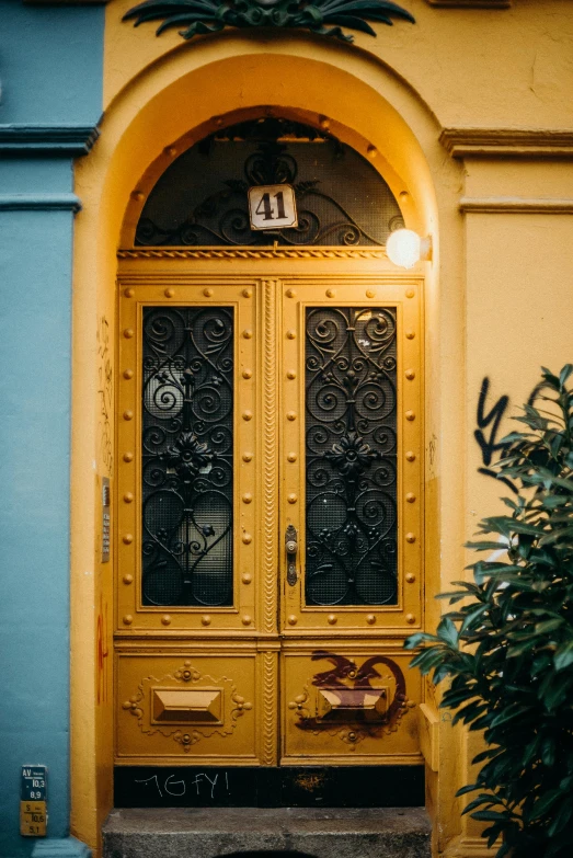 a cat sitting in front of a yellow door, by Konrad Witz, pexels contest winner, art nouveau, evening at dusk, gold color scheme, wrought iron, colorful house