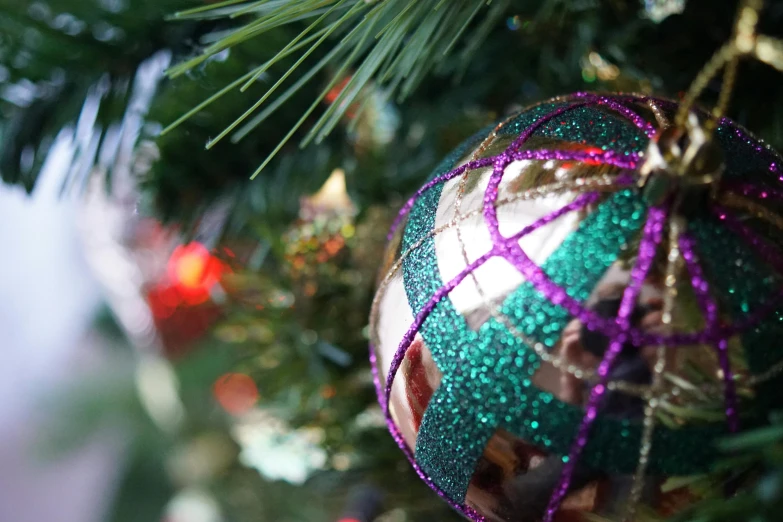 a close up of a christmas ornament on a tree, pexels, process art, green and purple, background image, ground level shot, decoration around the room