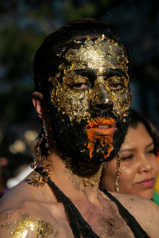 a man with gold paint on his face, an album cover, inspired by Francisco de Burgos Mantilla, reddit, pride parade, sukhothai costume, unkempt beard, face and body clearly visible