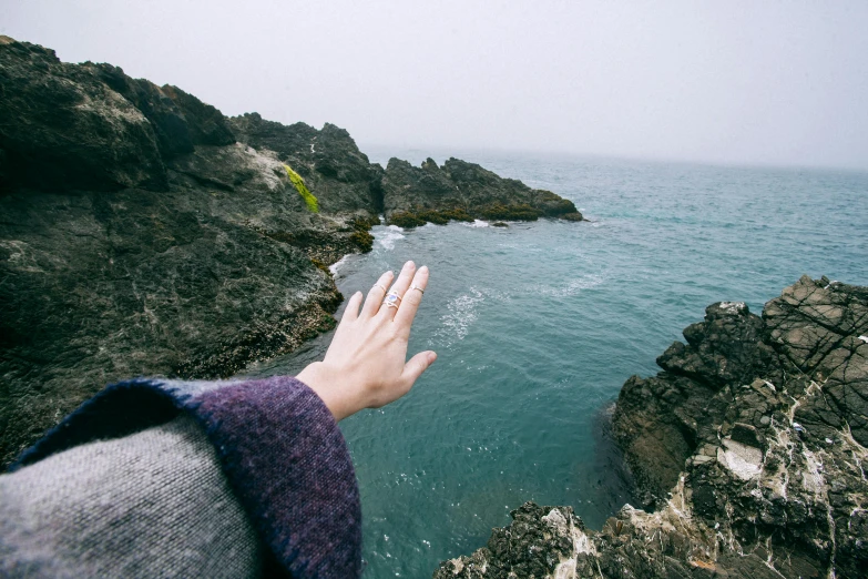 a close up of a person's hand near a body of water, the ocean, nanae kawahara, pointing to heaven, pembrokeshire