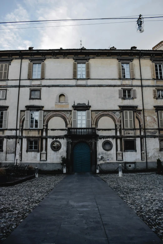 an old building with a blue door in front of it, inspired by Eliseu Visconti, renaissance, seen from a distance, mansion, buildings covered in black tar, front facing the camera