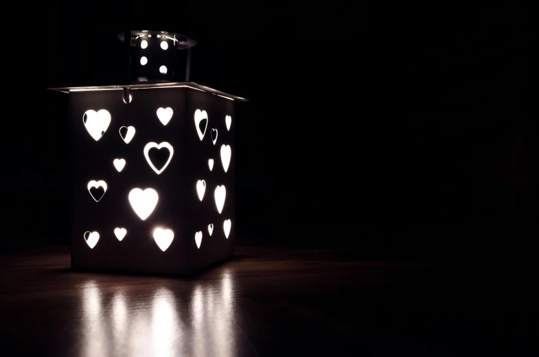 a black and white photo of a lantern with hearts on it, an ambient occlusion render, unsplash, minimalism, lit. 'the cube', made of glowing wax and ceramic, cosy atmosphere, soft light - n 9