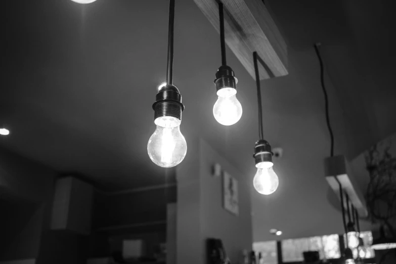 a bunch of light bulbs hanging from a ceiling, a black and white photo, small hipster coffee shop, three point lighting, lamp ( ( ( gym ) ) ) ), grayscale photography