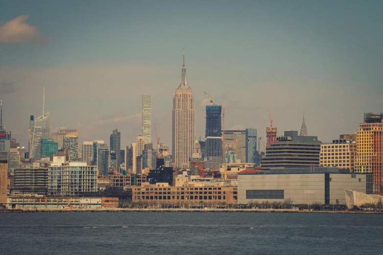 a large body of water with a city in the background, unsplash contest winner, hudson river school, tall metal towers, retro effect, brown, view from the sea