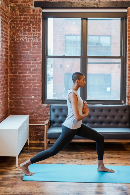 a woman standing on a yoga mat in front of a window, by Nina Hamnett, trending on unsplash, arabesque, jamel shabazz, architectural digest photo, running pose, high arches