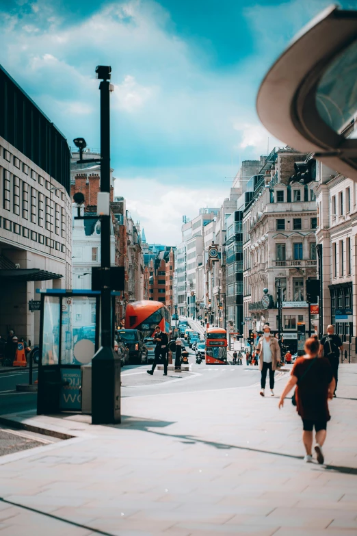 a group of people walking down a street next to tall buildings, united kingdom, fan favorite, stores, square